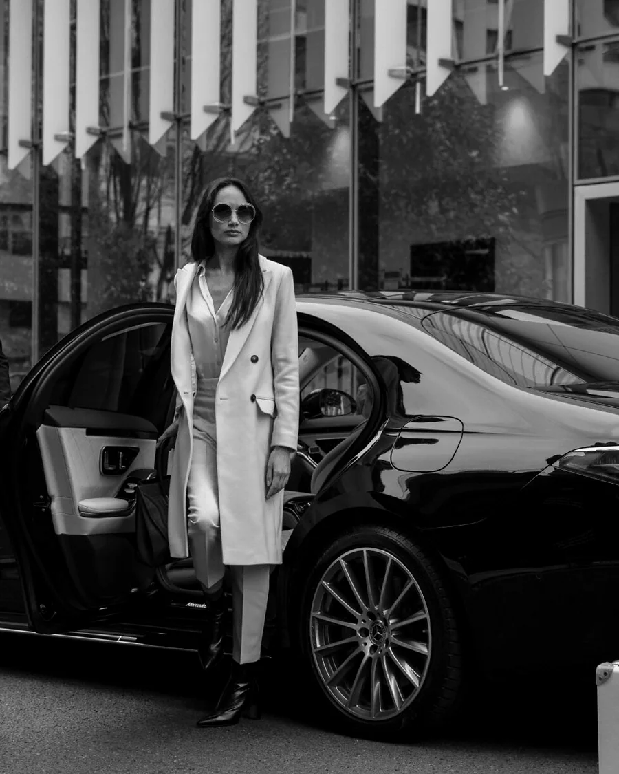 Executive passenger arriving beside a black 2026 Mercedes-Benz S 500 with a professional chauffeur
