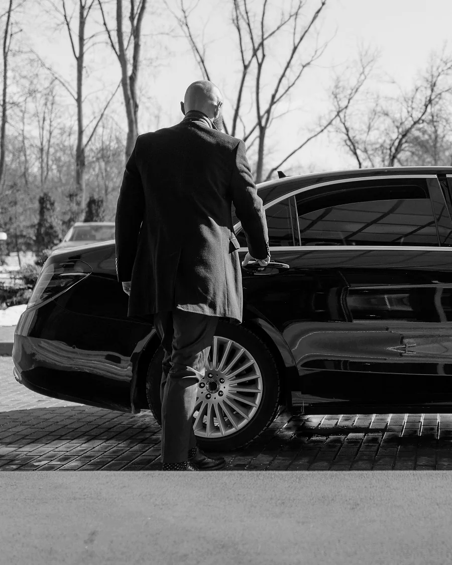 Executive arriving from a black 2026 Mercedes-Benz S 500 with a professional chauffeur